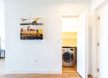 a laundry room with a washing machine and a painting on the wall